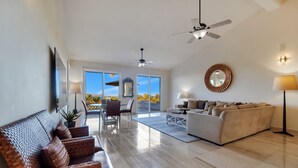 A spacious living area with a large sofa, a dining table with chairs, and a balcony with a view. - Amazing Cabo Villa-Beautiful Palmilla-Near Beach (San Jose del Cabo)