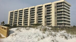 A multi-story hotel with balconies and a sandy beach in the foreground.