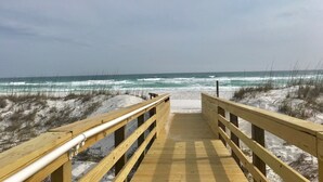 A wooden boardwalk leading to a beach with waves crashing onto the shore.
