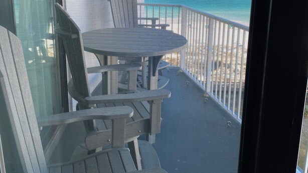 A balcony with a table and chairs, overlooking a body of water.