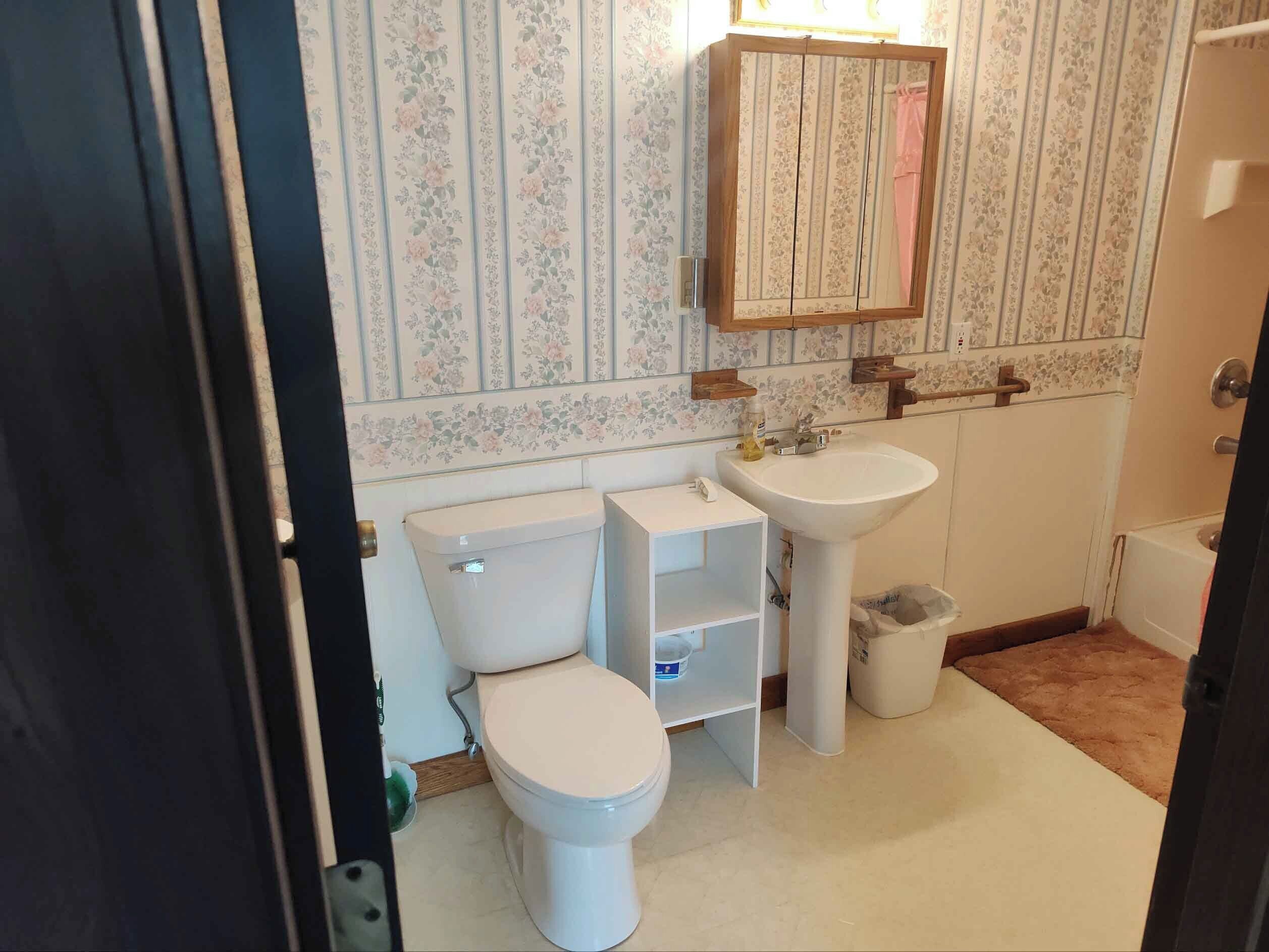 A bathroom with a toilet, sink, and cabinet.
