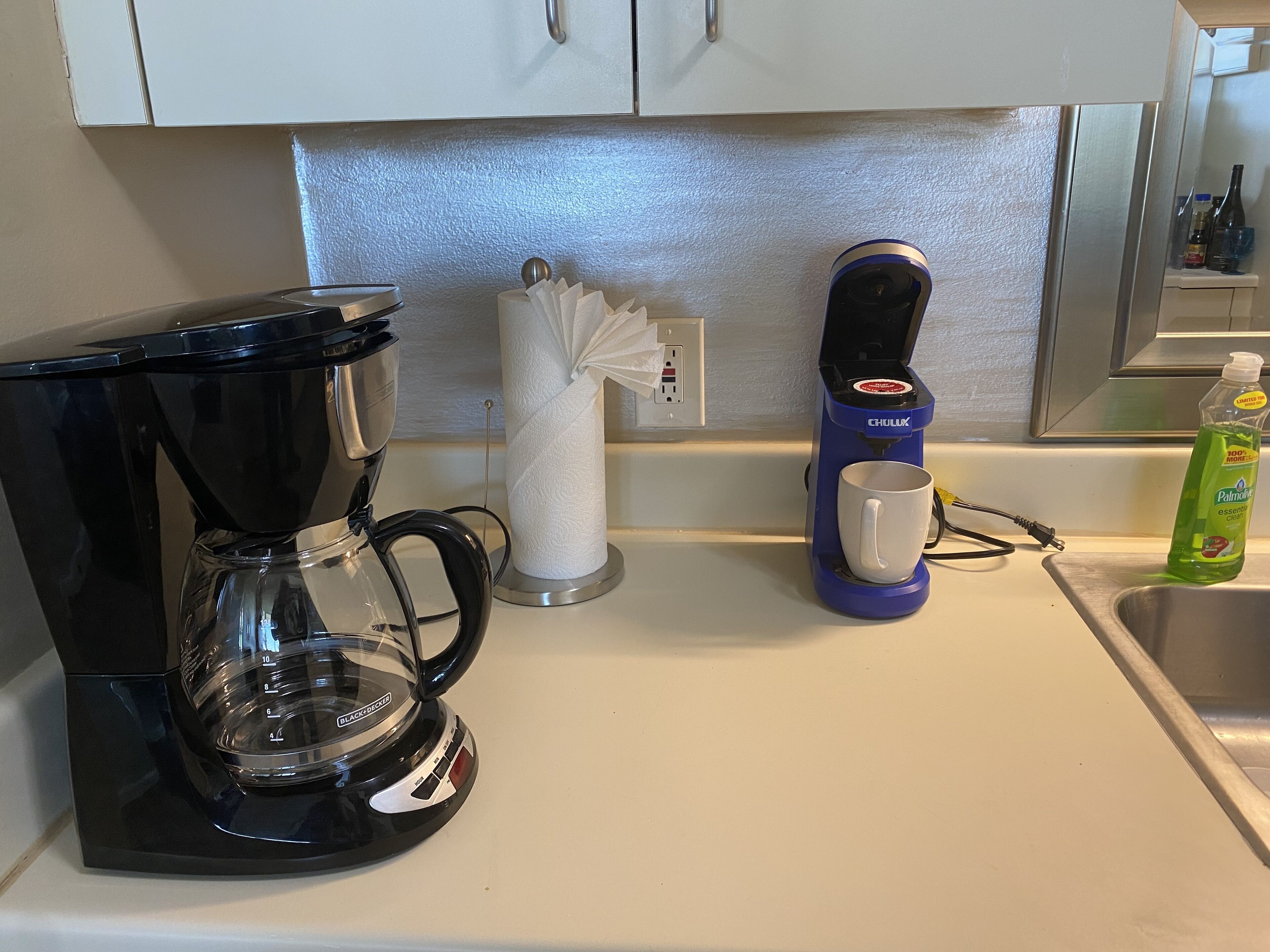 A kitchen with a coffee maker, a paper towel holder, and a water dispenser.