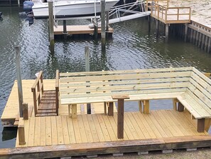 A wooden dock with a bench and a staircase leading to a boat.