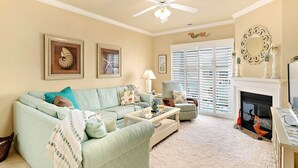 A living room with a sofa, armchair, coffee table, fireplace, and a ceiling fan. - Quiet 3BR Oasis in the Middle of Downtown Ocean City, Close to the Boardwalk. (Ocean City)