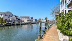 A waterfront property with a wooden dock, docked boats, and a row of houses along the water. - Quiet 3BR Oasis in the Middle of Downtown Ocean City, Close to the Boardwalk. (Ocean City)