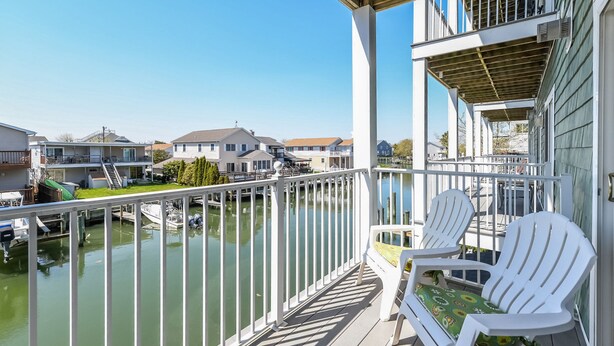 A balcony with white chairs and a view of a marina. - Quiet 3BR Oasis in the Middle of Downtown Ocean City, Close to the Boardwalk. (Ocean City)