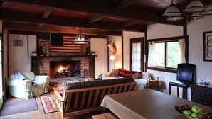 A cozy room with a fireplace, a sofa, a dining table, and a television.