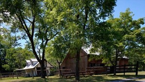 A rustic barn and a small building with a sloped roof, surrounded by trees and a wooden fence.