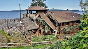 Une cabane en rondins dotée d’une terrasse en bois et d’un porche abrité, avec vue sur un lac.