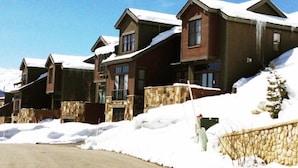 A row of wooden cabins with stone foundations, set against a snowy landscape.