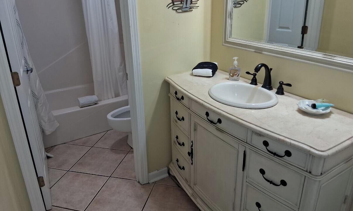 A bathroom with a white sink, a mirror, a towel rack, and a shower curtain.