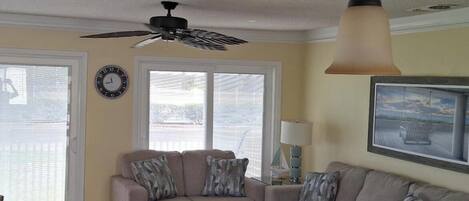 A living room with a ceiling fan, two couches, a glass coffee table, and a chair.