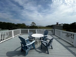 A deck with a white railing, a round table, and four chairs.