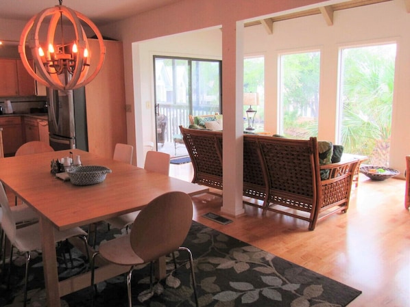 A dining area with a wooden table, chairs, a chandelier, and wicker chairs.