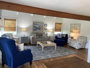 A living room with a sofa, armchairs, a coffee table, and a patterned rug.