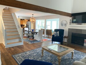 A spacious living area with a staircase, a fireplace, and a television.