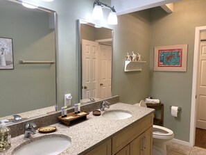 A bathroom with two sinks, a large mirror, and a toilet.