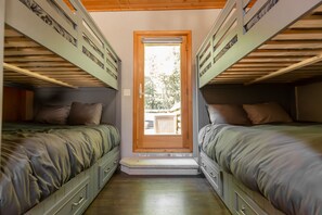 A compact room with bunk beds, a wooden door leading outside, and a small step at the entrance.
