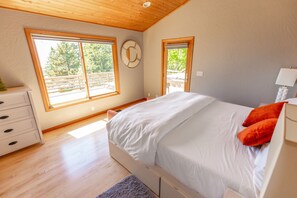 Un dormitorio con cama, cómoda, ventana y puerta.