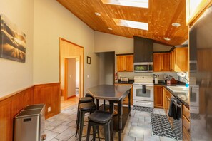 Une cuisine moderne avec des meubles en bois, un réfrigérateur en acier inoxydable et un grand îlot central doté de tabourets.