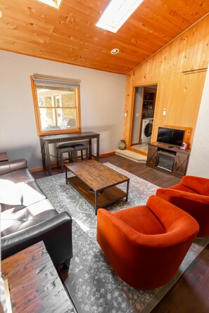 Un salon chaleureux avec un plafond en bois, un canapé, une table basse et un meuble pour la télévision.