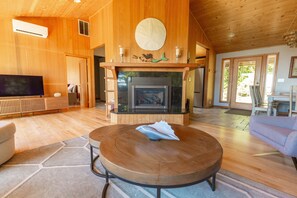 A spacious living room with a fireplace, wooden flooring, and a television.