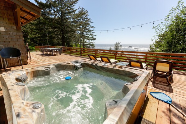 Un jacuzzi en una terraza de madera con vista al océano.