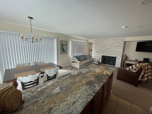 A modern living room with a large island, a fireplace, a sofa, and a television.