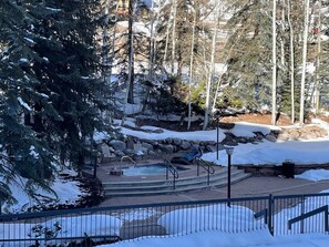 Espacio exterior cubierto de nieve con un jacuzzi, asientos y un muro de piedra.