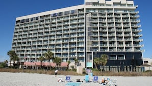 A multi-story hotel with numerous balconies, a beachside location, and outdoor seating areas. - A SLICE OF PARADISE! - Direct Oceanfront condo (Myrtle Beach)