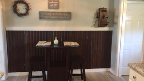 Una cocina con una pared de acento en madera oscura, una araña, un letrero de bienvenida, una cámara antigua y una guirnalda.