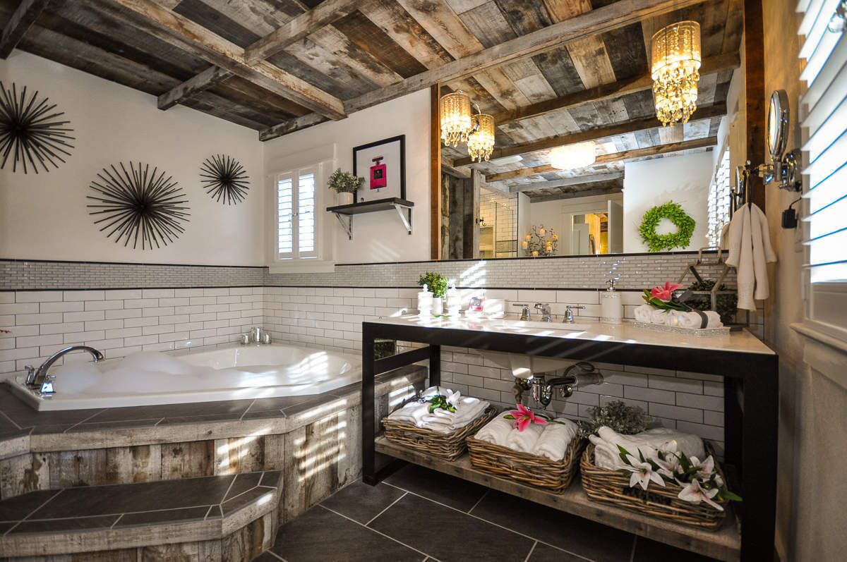 A bathroom with a large bathtub, a vanity with a mirror, and decorative wall sconces.