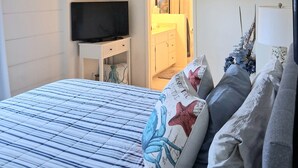 A bedroom with a bed, a television on a stand, a ceiling fan, and a door leading to a bathroom. -  Laguna Home at Shaw's Cove, Ocean View, Quiet street, Short walk to beaches



 (Laguna Beach)