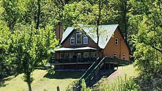 A large house with a balcony and a staircase leading up to it, surrounded by trees. - White River Bank Cabin!Eagle Watching, World Class Trout Fishing Off  The Dock,  (Flippin)