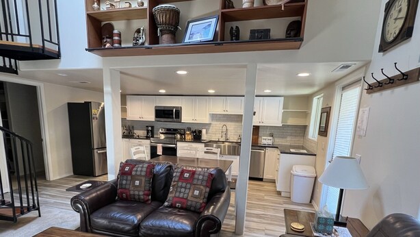A modern living room with a leather sofa, a wooden coffee table, and a kitchen in the background.