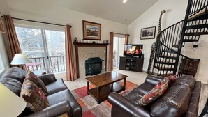 A living room with a fireplace, leather sofas, a coffee table, and a staircase.