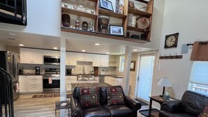 A spacious living area with a leather sofa, a wooden coffee table, and a kitchen in the background.
