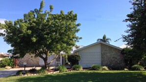 Una casa residencial con fachada de piedra, un garaje y un gran árbol en el jardín delantero.