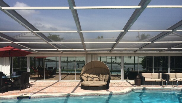 Un área de piscina interior con un patio cubierto, asientos y vista al agua.