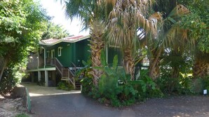 A green building with a red roof, surrounded by lush greenery and palm trees.