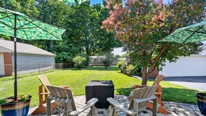 A patio with two Adirondack chairs, a covered table, and a large umbrella.
