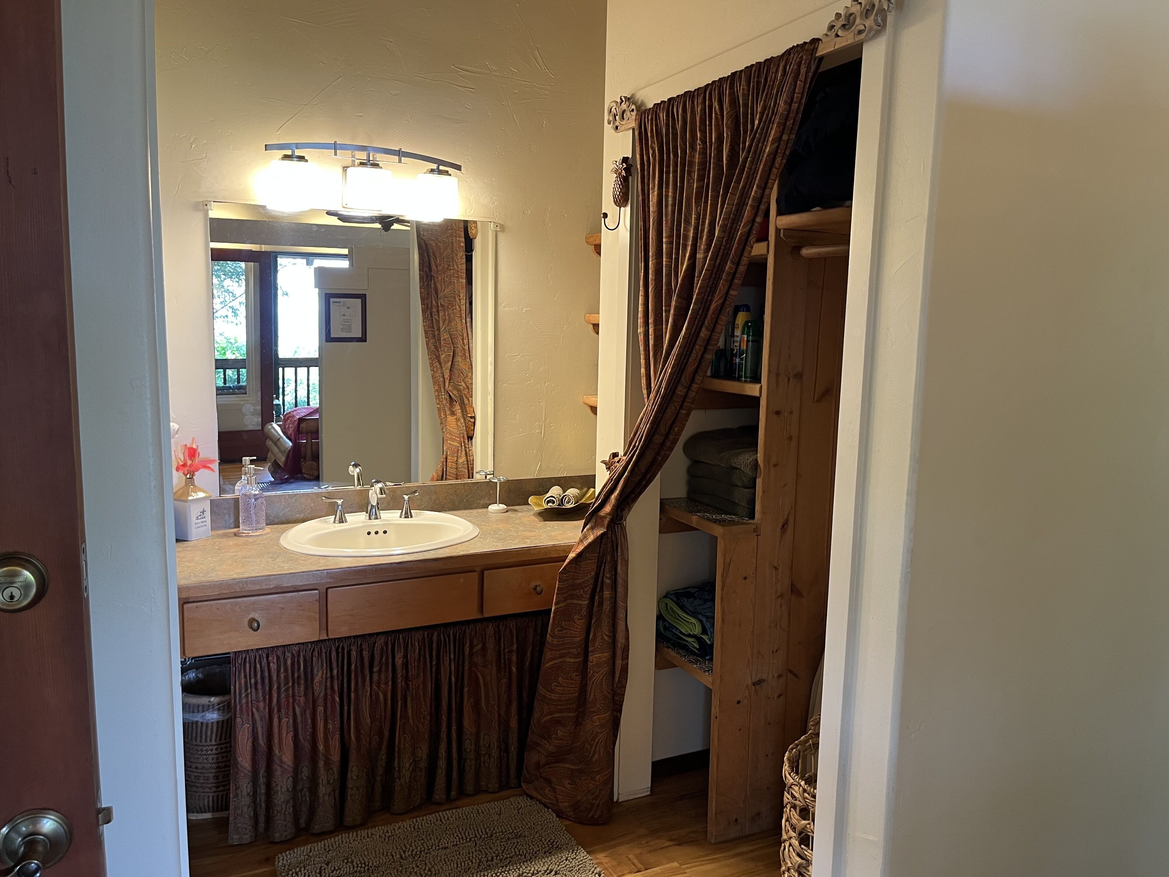 A bathroom with a double sink, a mirror, and a wooden shelf with towels.