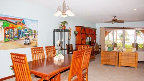 A dining area with a wooden table and chairs, a ceiling fan, and a painting of a street scene on the wall. - Oceanfront First Floor 2 Bed/2 Bath - Free use of Kayaks (San Pedro)