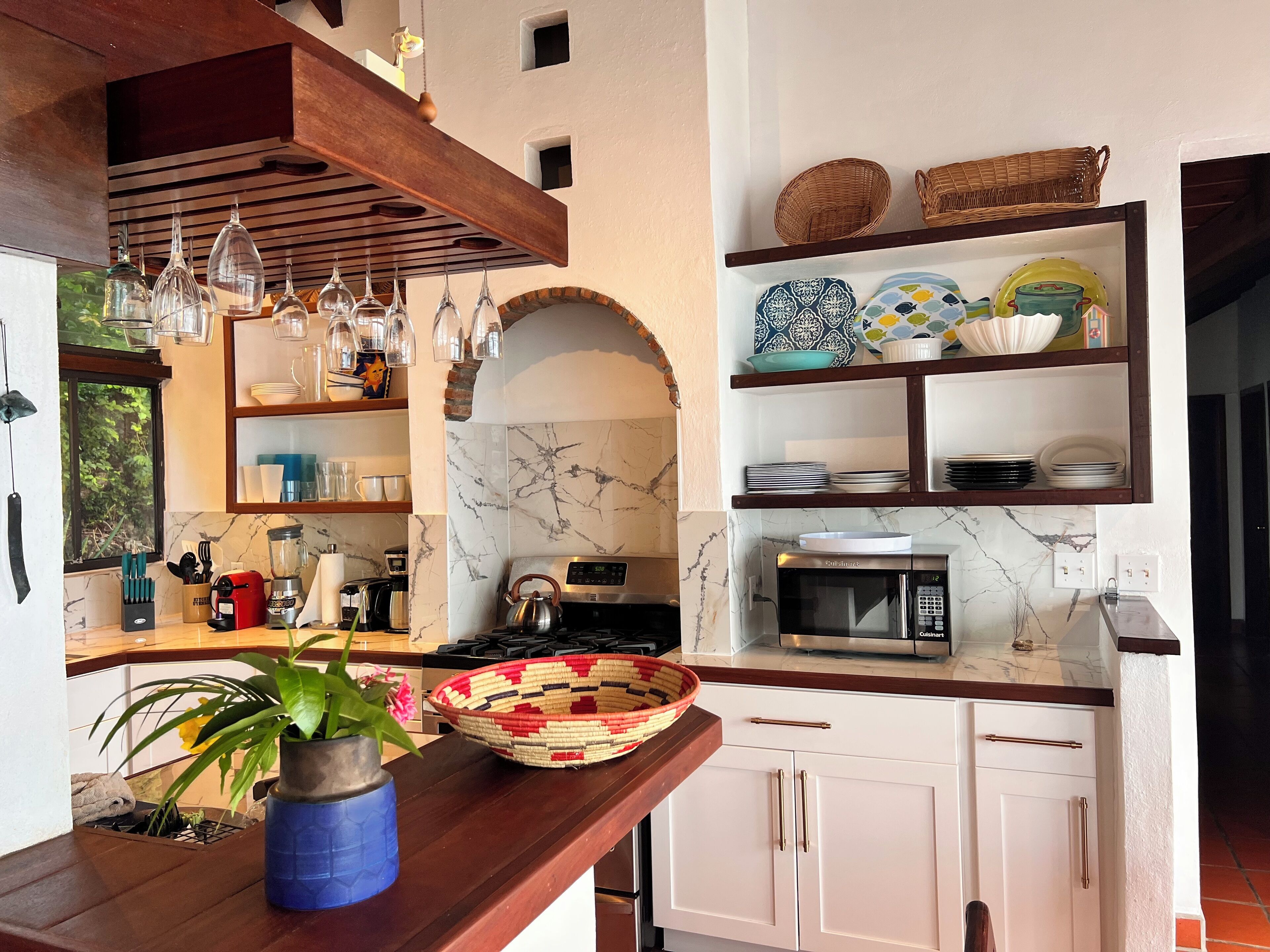 A kitchen with a marble backsplash, a microwave, a stove, and various kitchen utensils.
