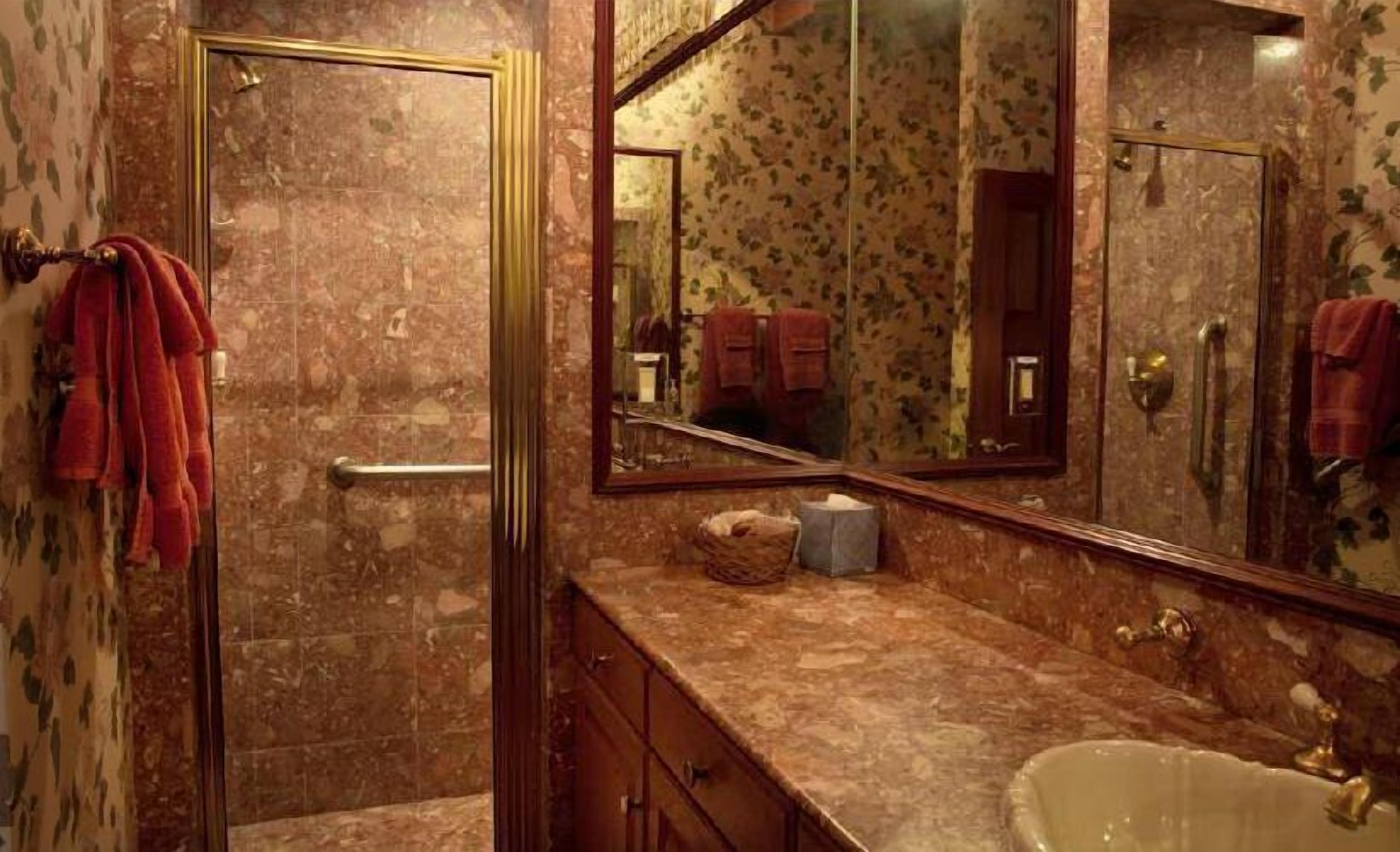 A bathroom with a marble countertop, a sink, and a mirror.