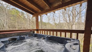 Ein Whirlpool mit einer Holzterrasse und Blick auf einen Wald.