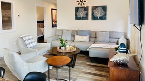 Un salon moderne comprenant un canapé, une table basse et un téléviseur fixé au mur.