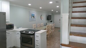 A kitchen with white cabinets, a microwave, an oven, and a dining area with wooden chairs and a table. - TOWNHOUSE IN BEAUTIFUL SUNNYSIDE BEACH (Panama City Beach)