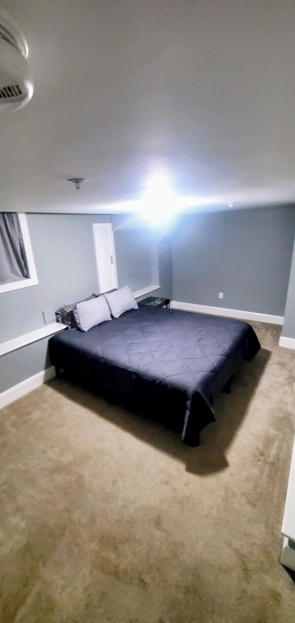 A bedroom with a large bed, a window with curtains, and a ceiling light.