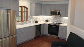 Una cocina moderna con armarios grises, electrodomésticos de acero inoxidable y un salpicadero de azulejos.